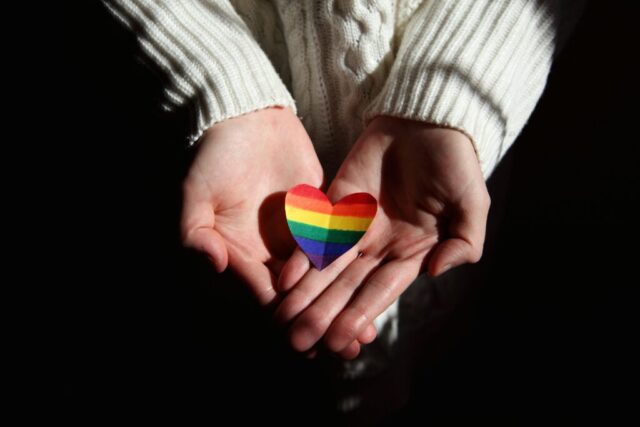Hands offering a rainbow heart symbolizing love and LGBTQ+ pride.
